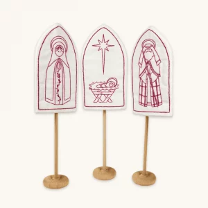 A complete Holy Family with Mary, Joseph and baby Jesus redwork embroidery kit displayed on the included wooden stands.